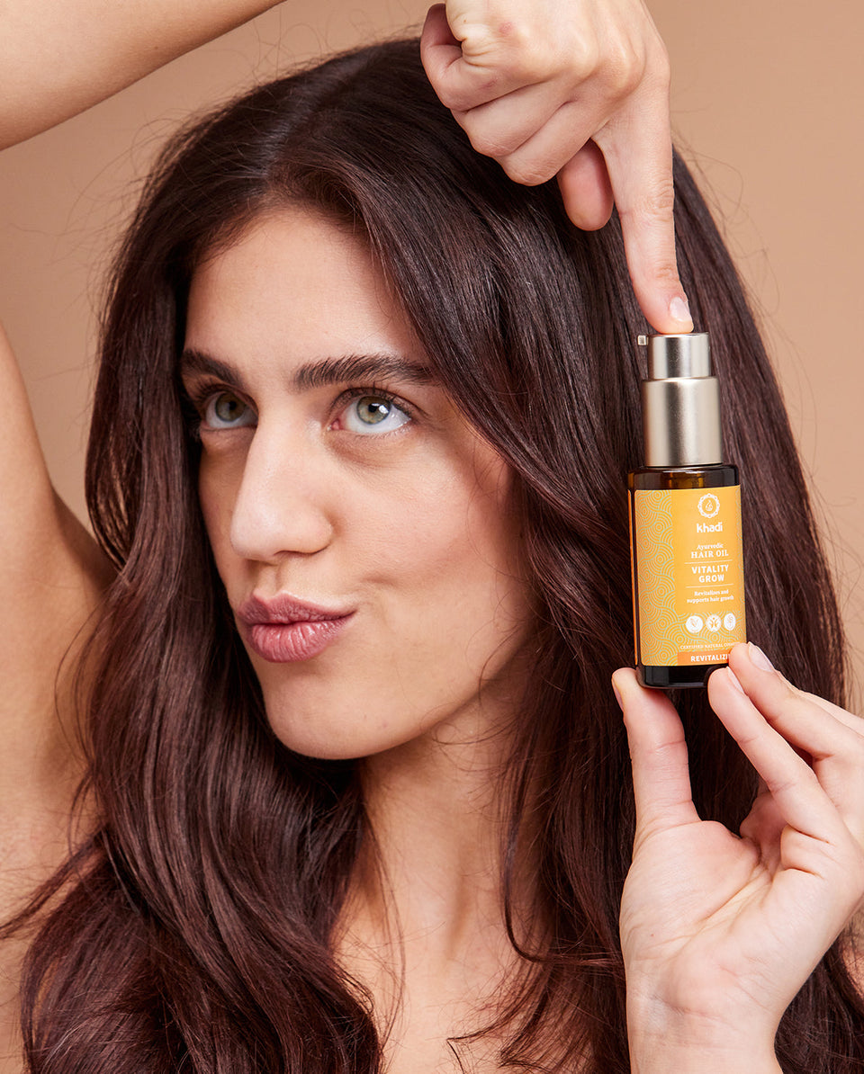 Image of Orange Vitality Hair Oil application, hand model by khadi