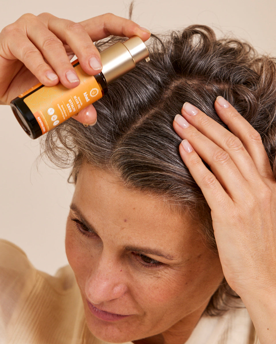 Image of Orange Vitality Hair Oil application, hand model by khadi